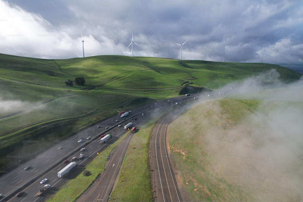 a view of a highway with wind turbines in the background