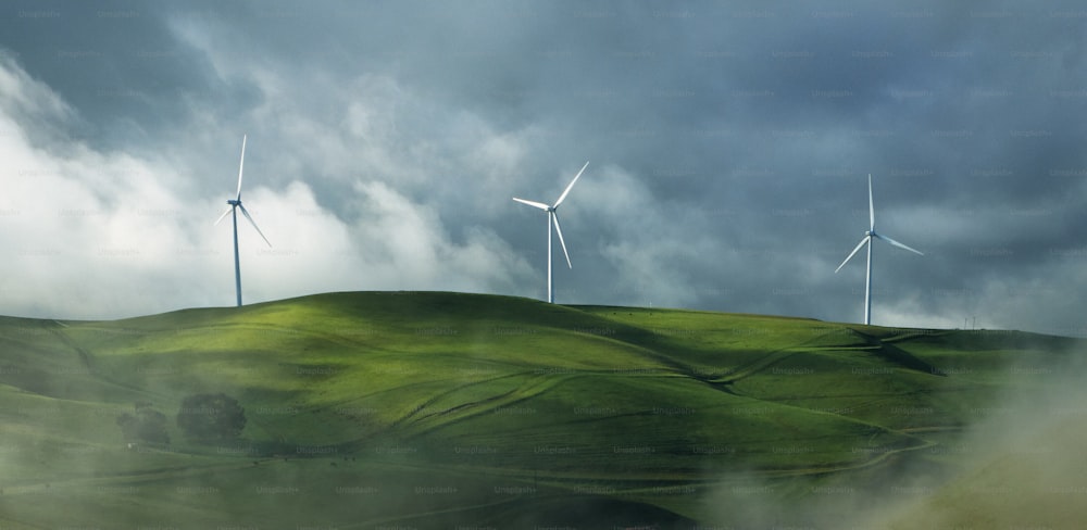 a group of wind turbines on a green hill