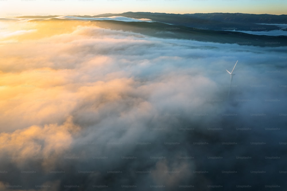 a wind turbine in the middle of a sea of clouds