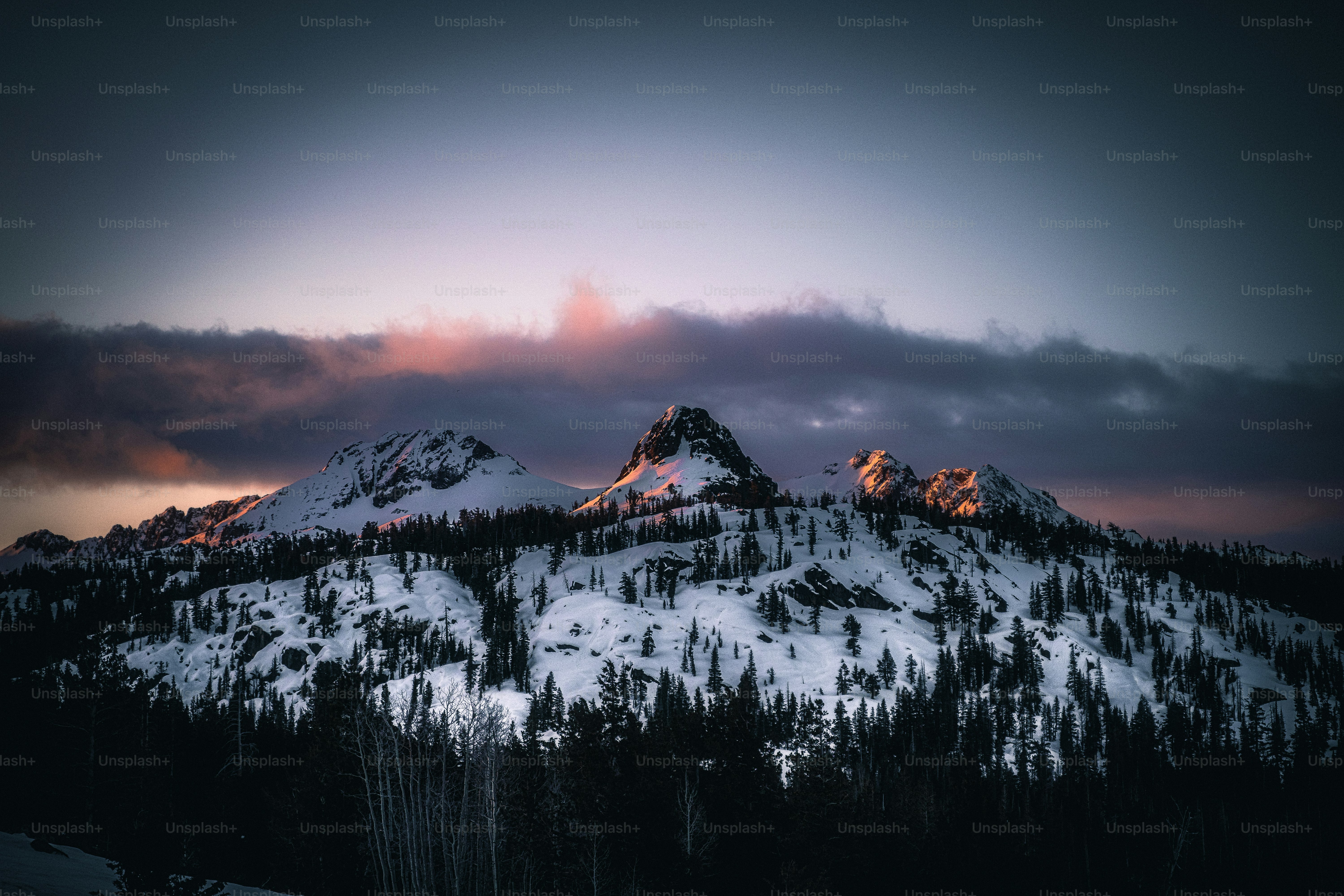 a mountain covered in snow under a cloudy sky