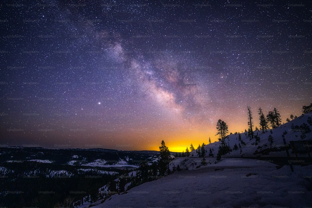 a view of the night sky over a snowy mountain