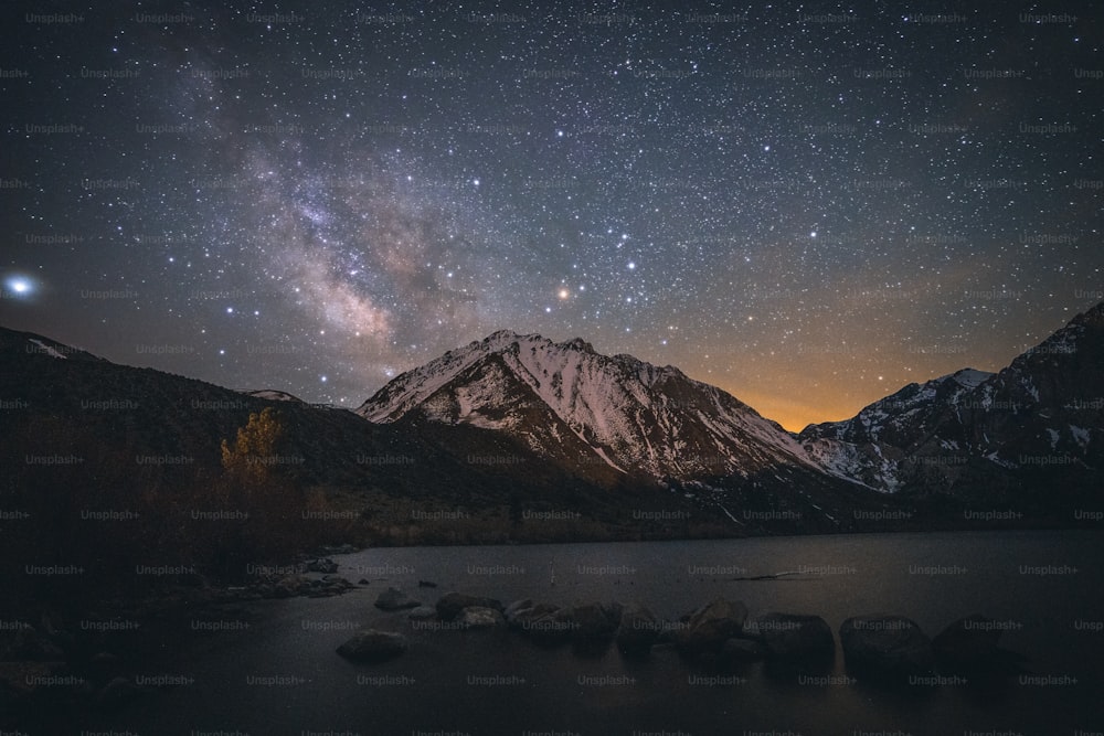 El cielo nocturno sobre una cordillera y un lago