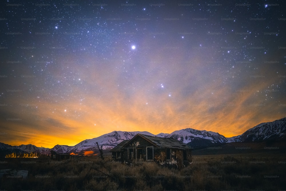 a house in the middle of a field with mountains in the background