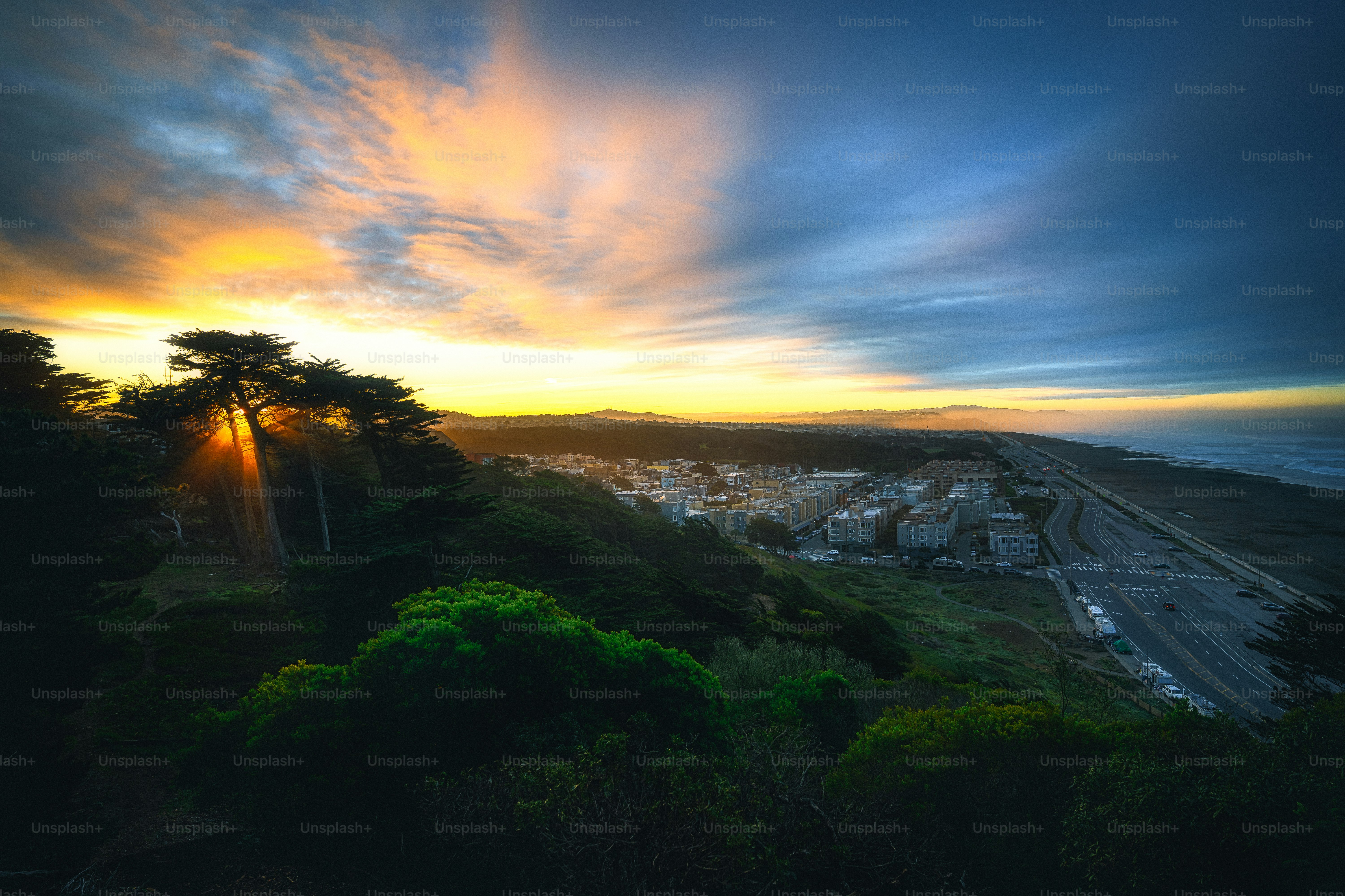 the sun is setting over a city on a hill