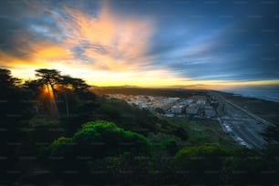 the sun is setting over a city on a hill