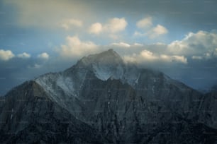 a very tall mountain covered in snow under a cloudy sky