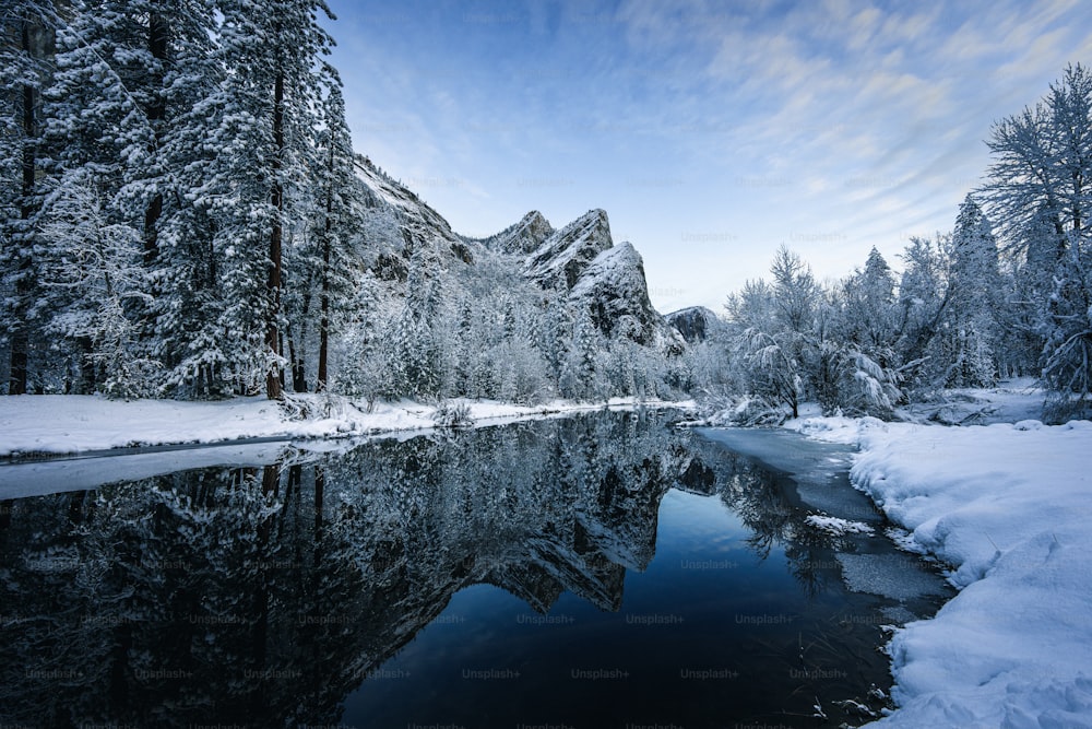 um rio cercado por árvores cobertas de neve e montanhas