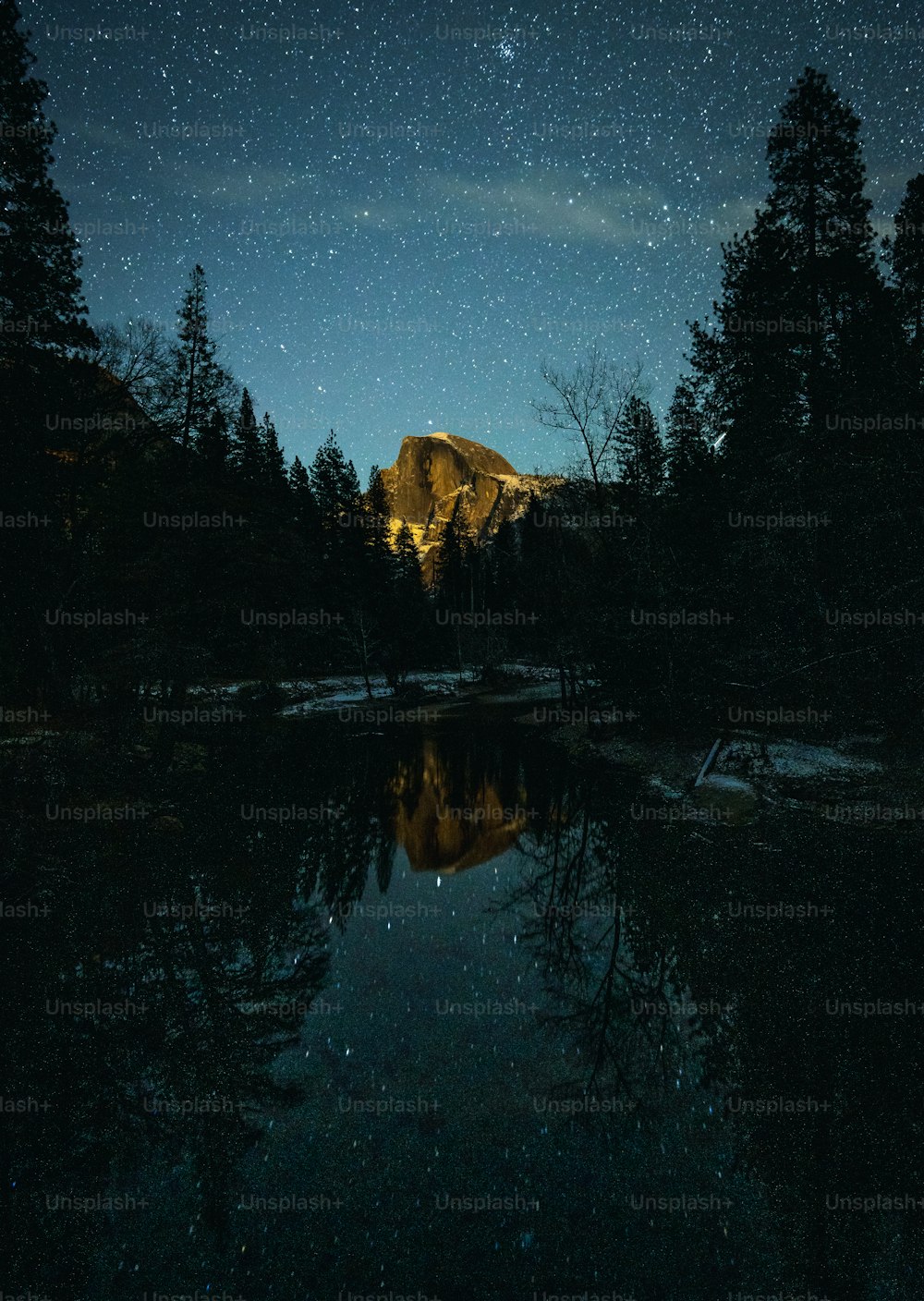 El cielo nocturno se refleja en el agua quieta de un lago de montaña