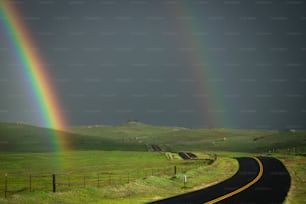 two rainbows in the sky over a country road