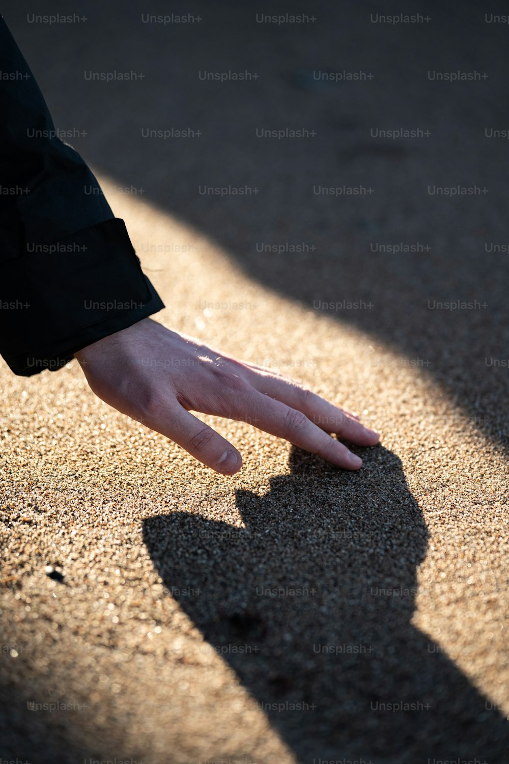 Die Hand einer Person, die nach etwas im Sand greift