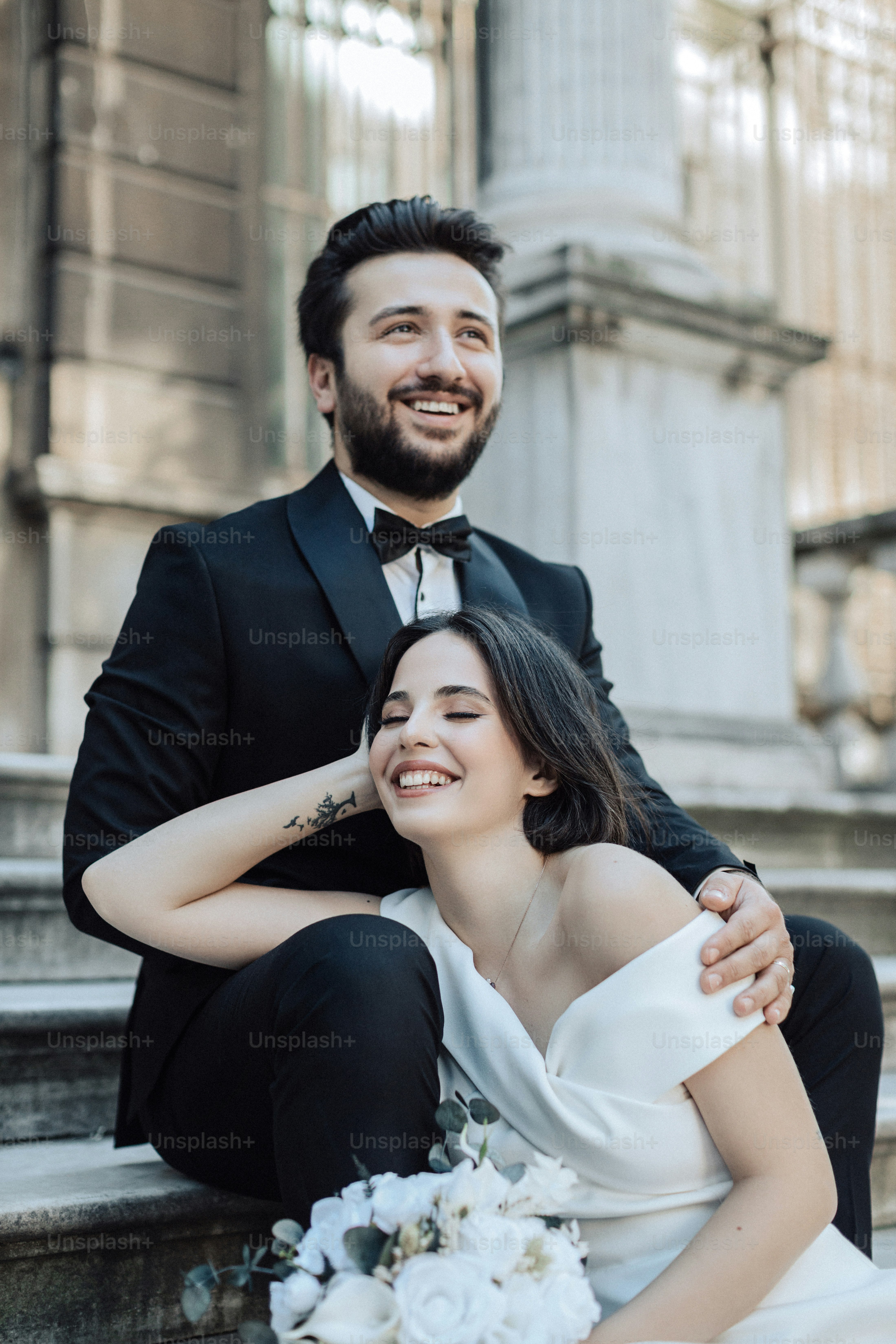 a bride and groom sitting on the steps of a building