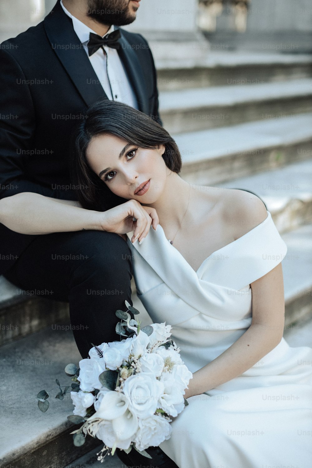 a bride and groom sitting on the steps of a building