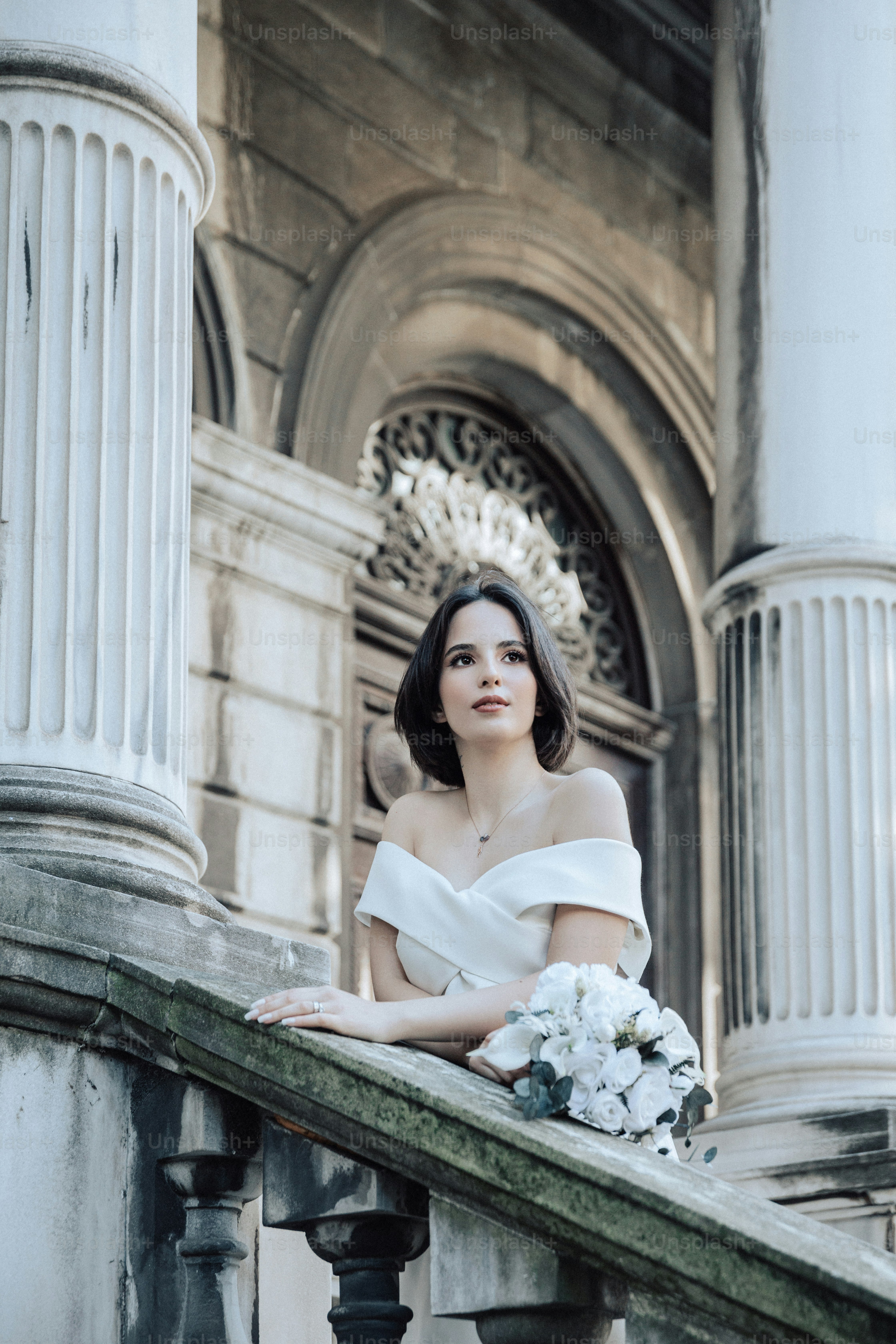 a woman in a white dress standing on a balcony