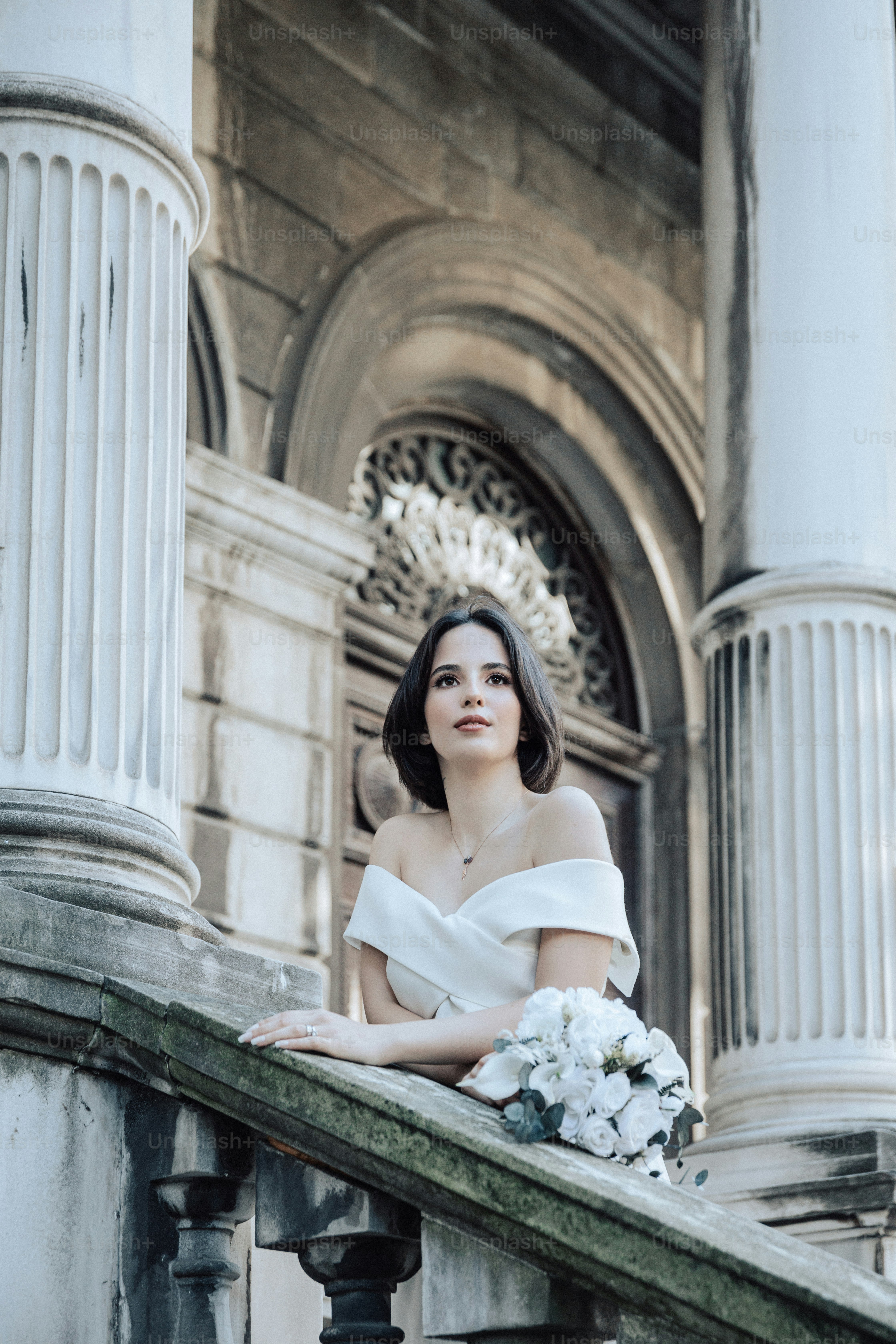 uma mulher em um vestido branco sentado em uma varanda
