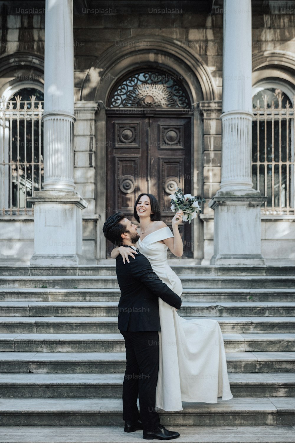a bride and groom standing on the steps of a building
