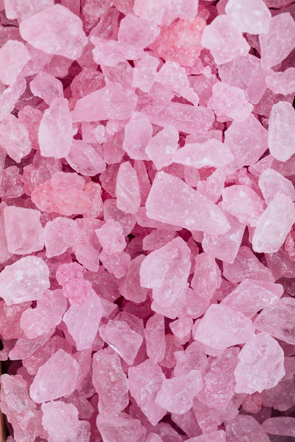 uma pilha de cristais de açúcar rosa sentados em cima de uma mesa