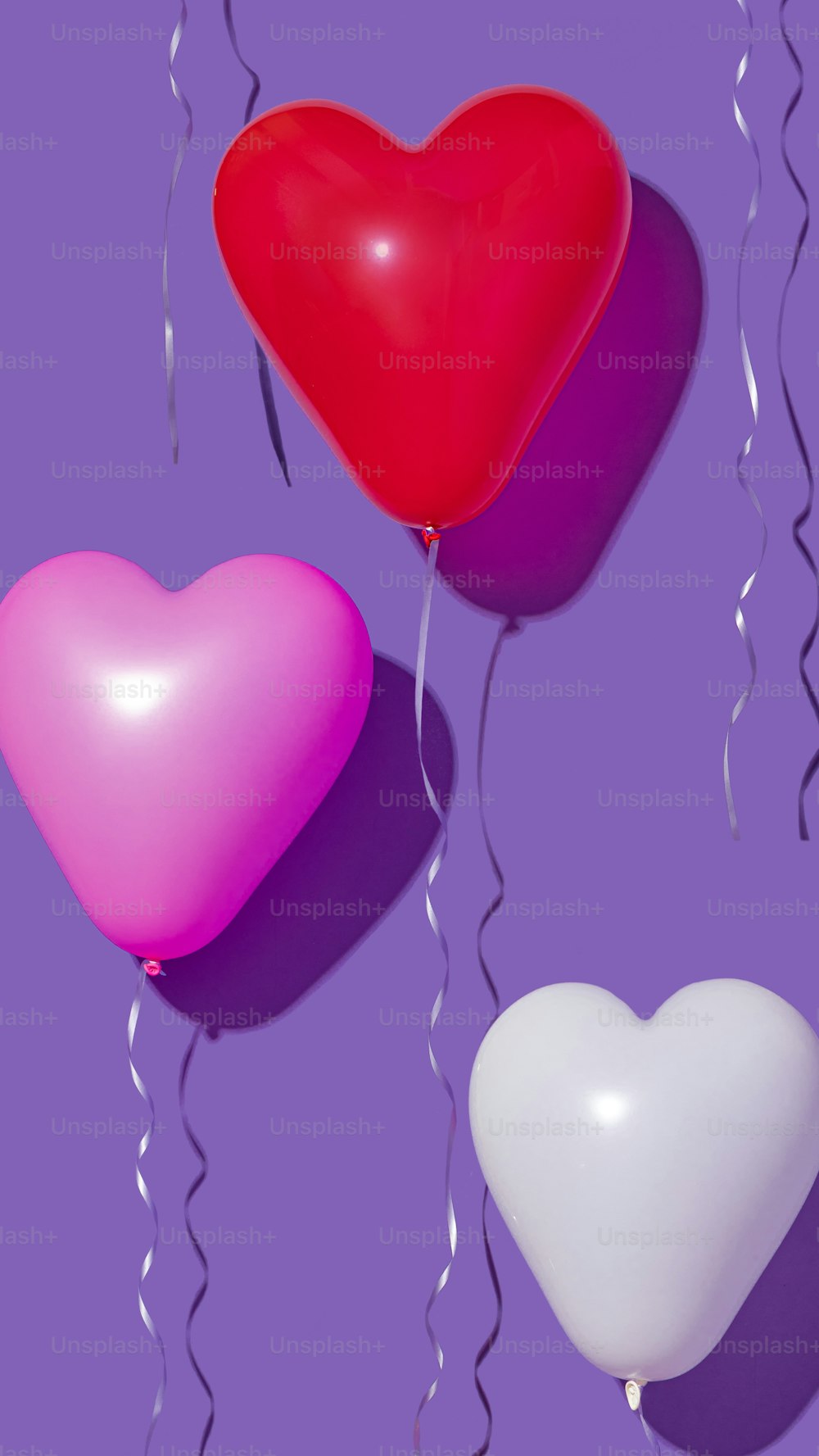 three heart shaped balloons floating in the air
