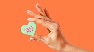 a woman's hand holding a candy heart that says can u not