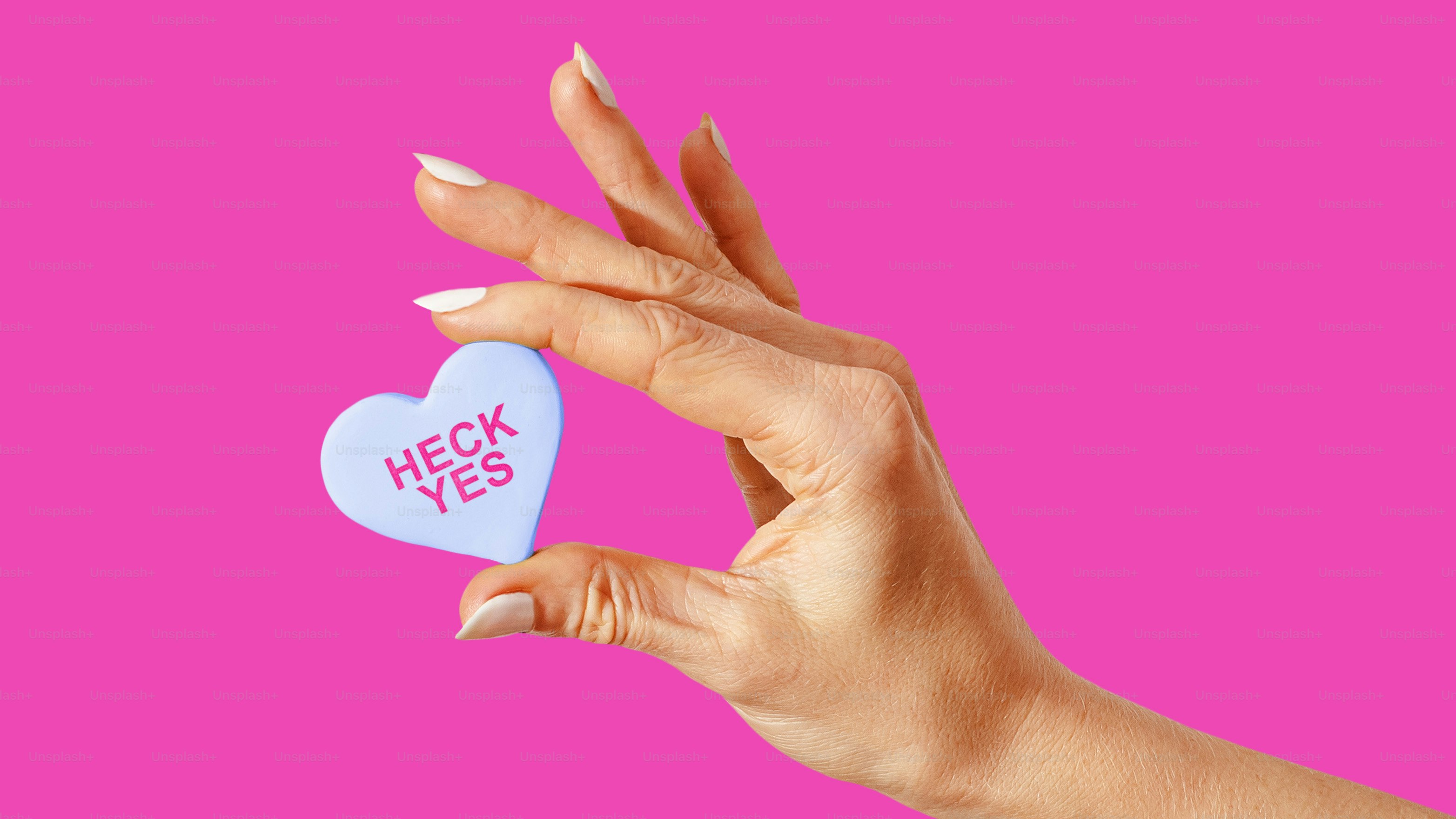 La mano de una mujer sosteniendo un caramelo en forma de corazón