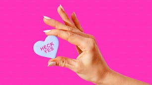 a woman's hand holding a heart shaped candy