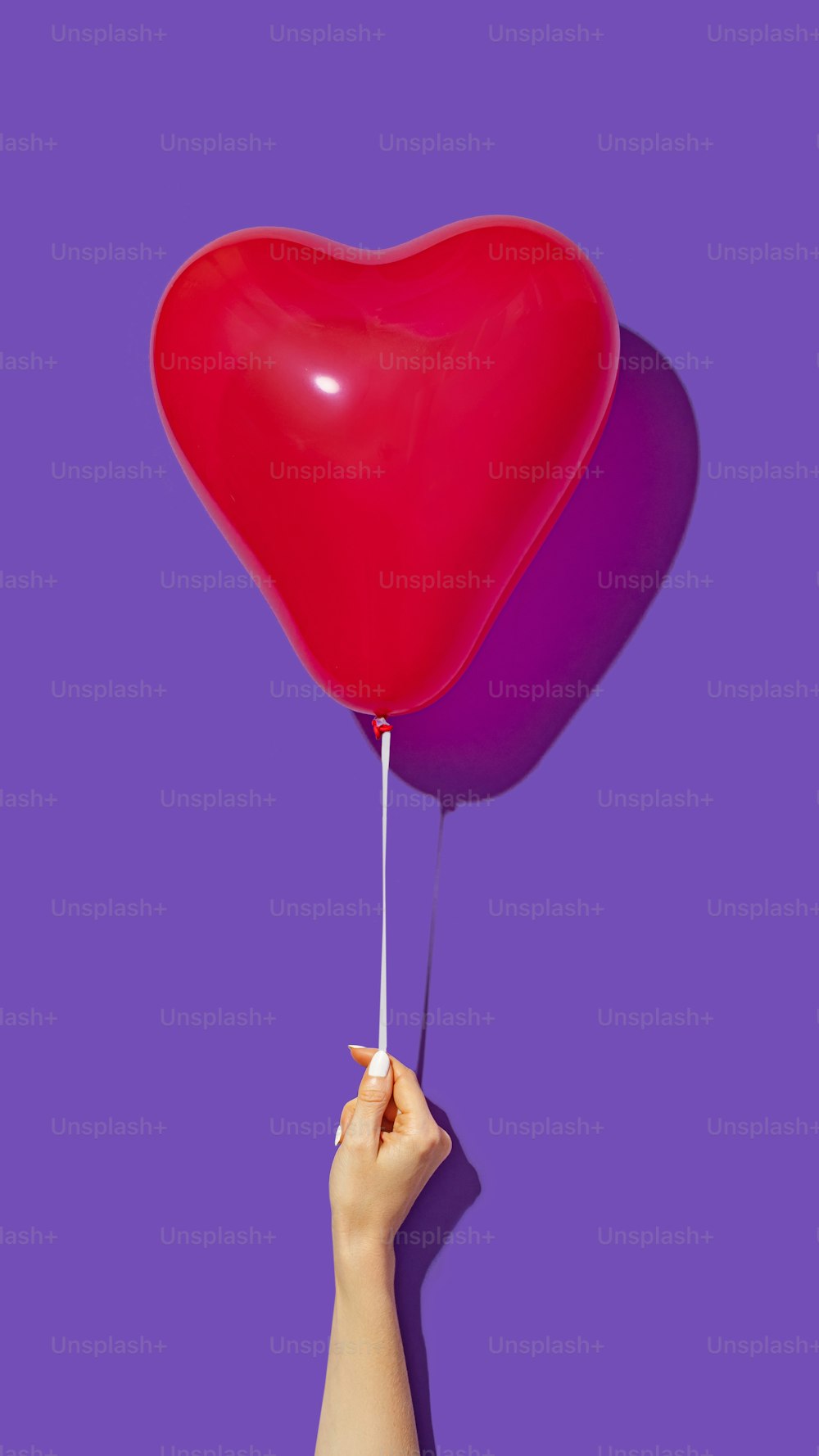 Eine Person, die einen herzförmigen Ballon in der Luft hält
