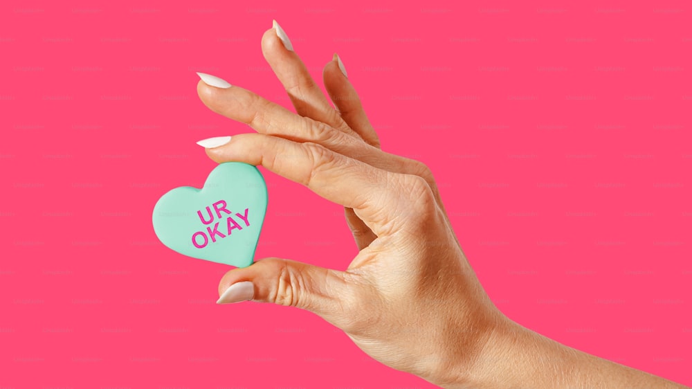 a woman's hand holding a heart shaped cookie with the words ur okay on