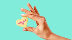 a woman's hand holding a candy heart with the word single af on it