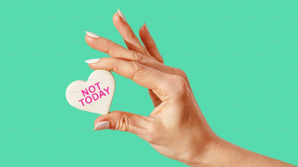 a woman's hand holding a candy heart with the words not today written on
