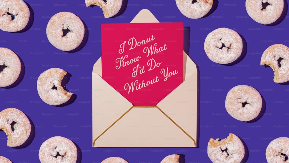 a pink envelope with a pink heart on it surrounded by donuts