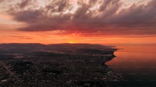 the sun is setting over a city and a body of water