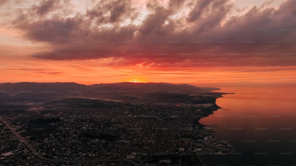 the sun is setting over a city and a body of water