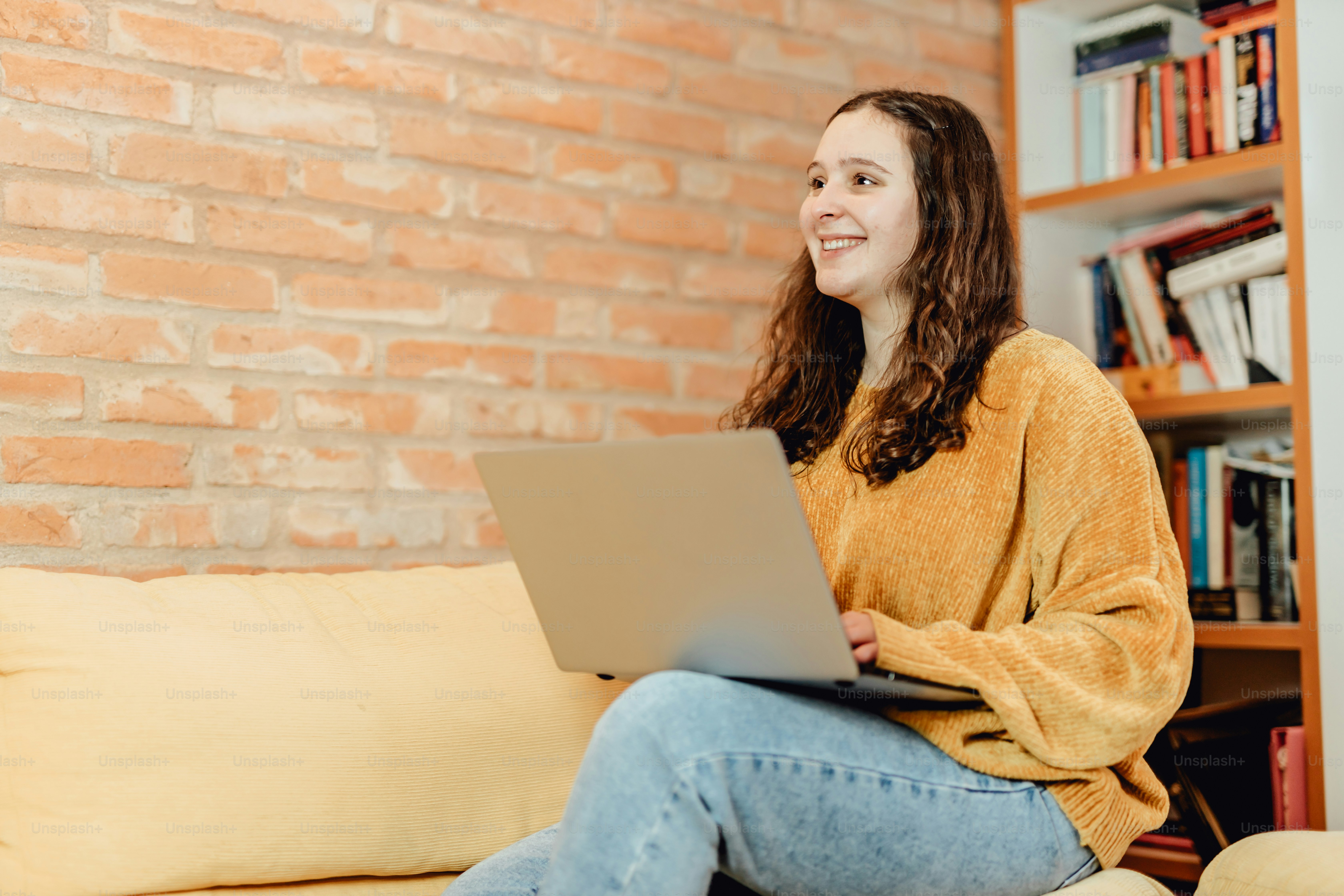 uma mulher sentada em um sofá usando um computador portátil