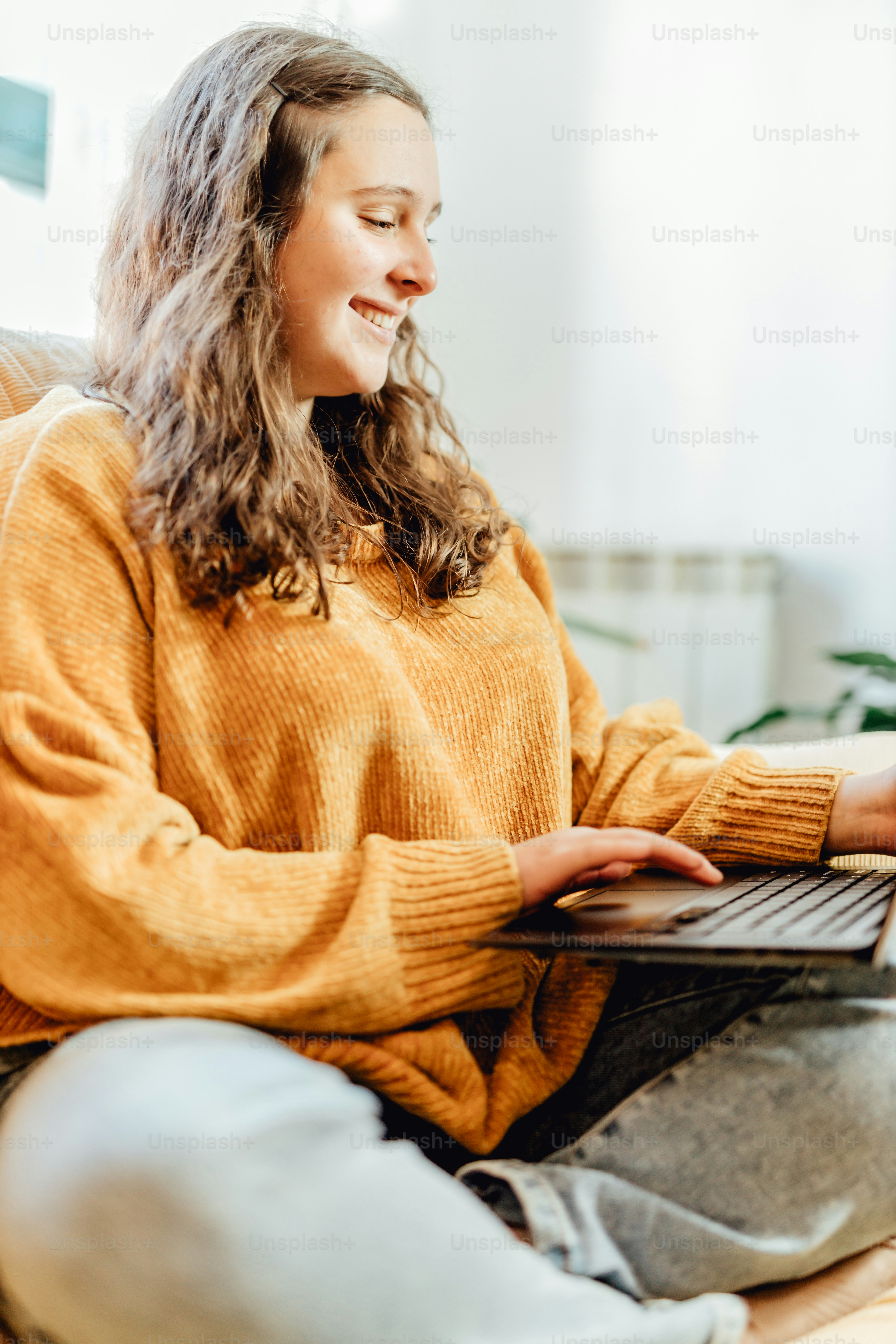 uma mulher sentada em um sofá usando um computador portátil