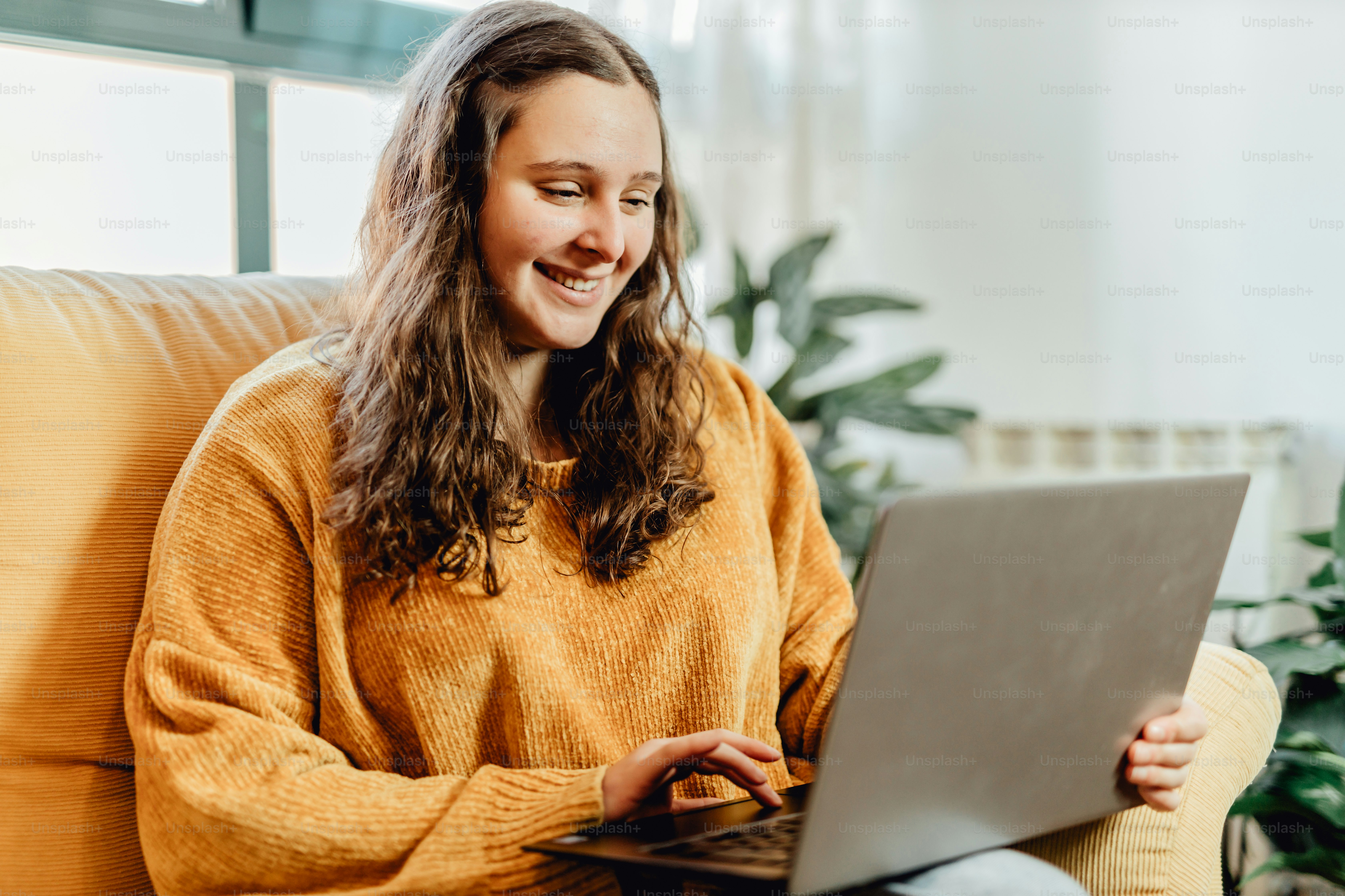 ノートパソコンを使ってソファに座っている女性