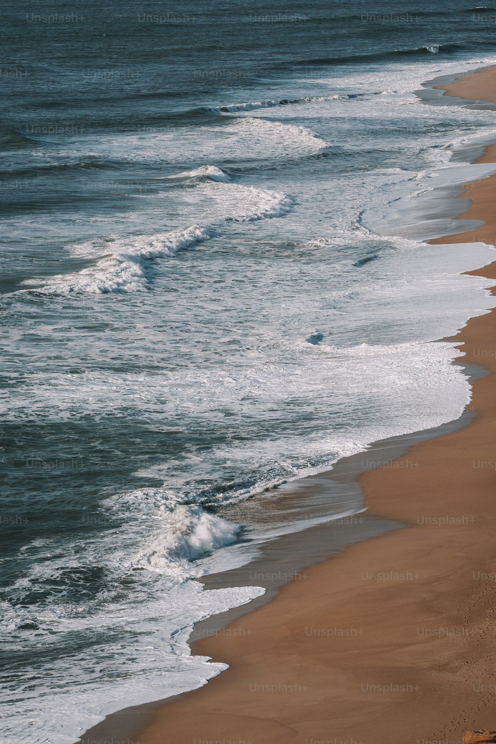 a sandy beach with waves coming in to shore