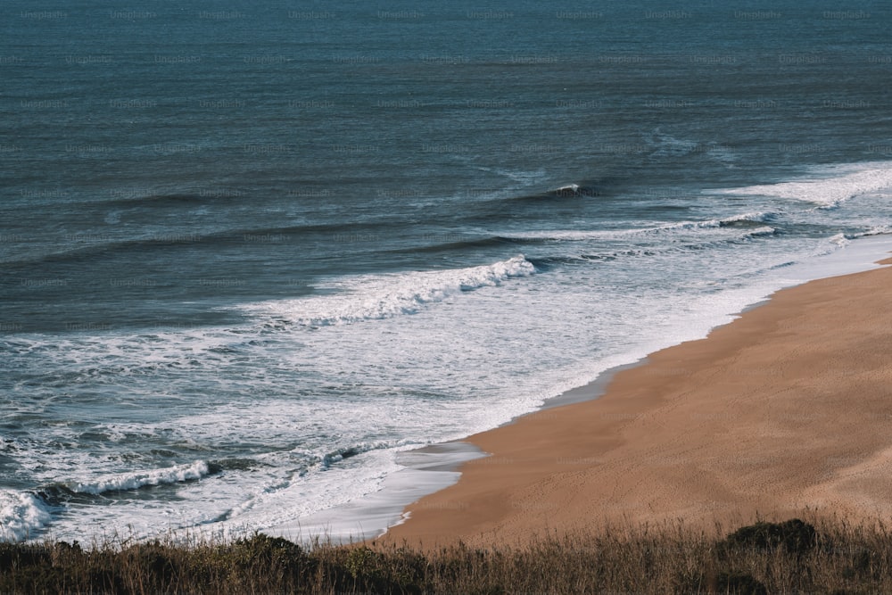 Blick auf einen Strand mit Wellen, die vom Meer kommen
