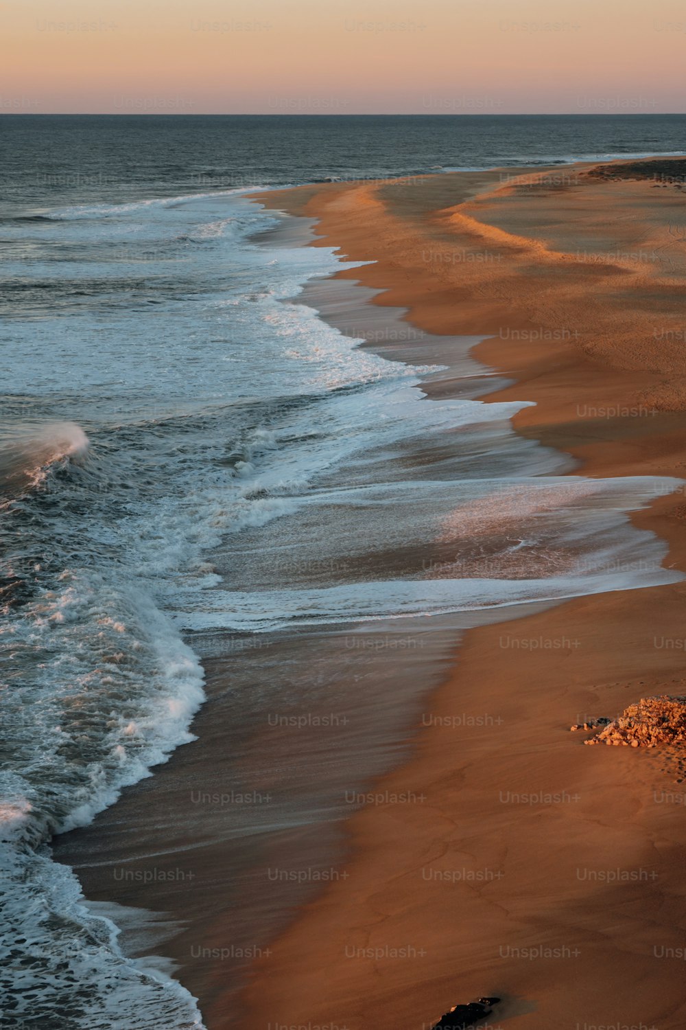 a sandy beach with waves coming in to shore