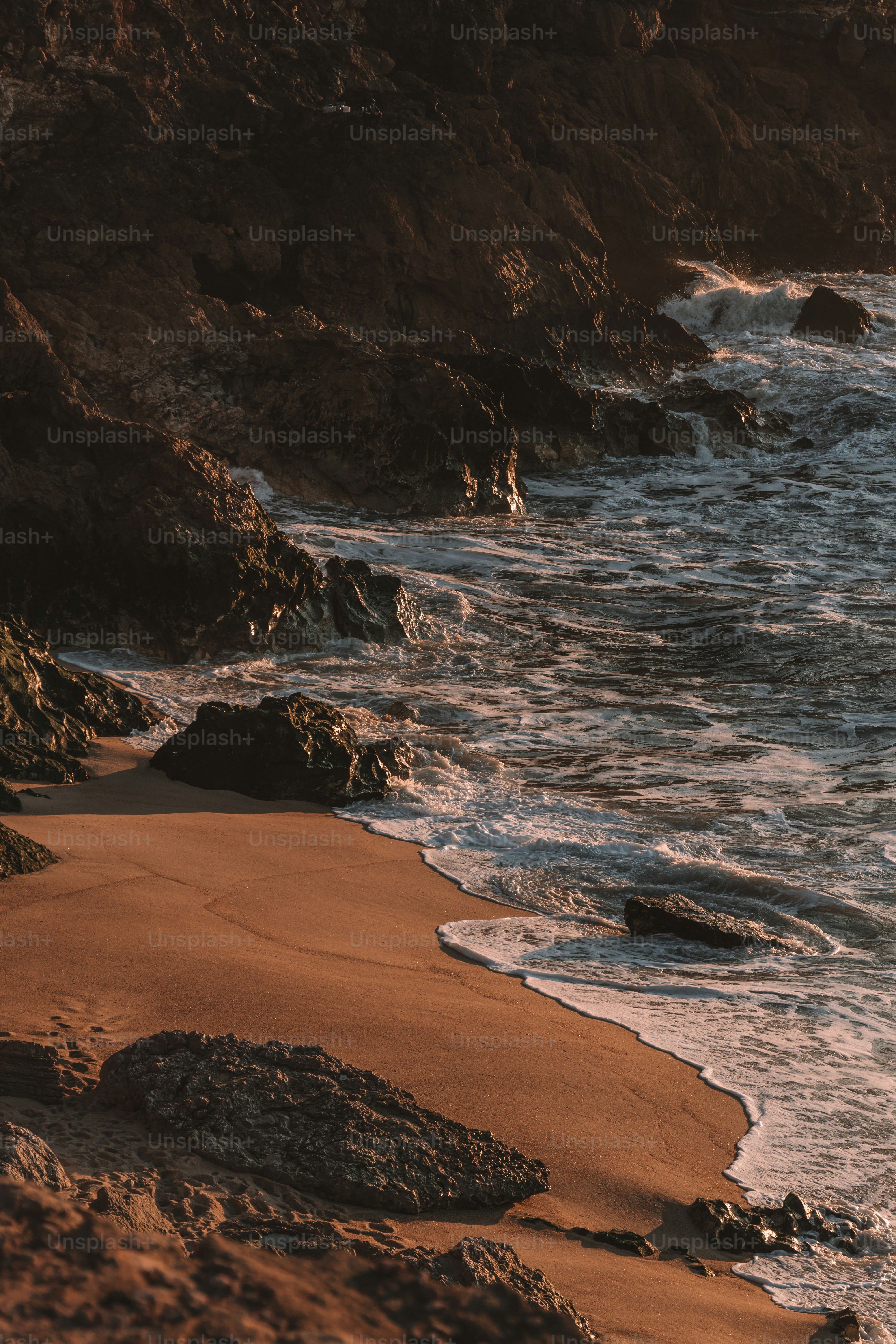 a sandy beach next to the ocean with waves coming in