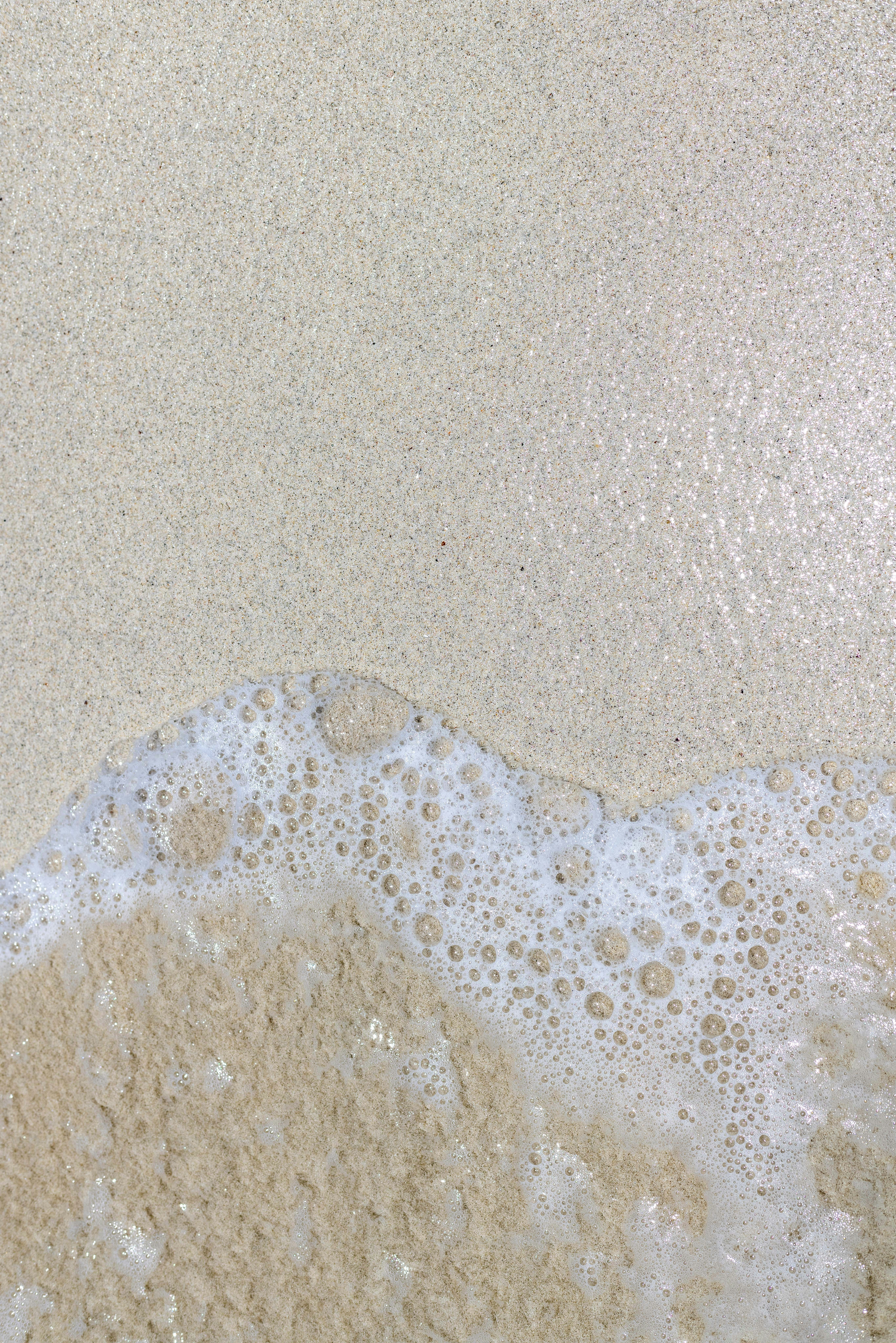 uma praia de areia com uma onda que vem para a costa