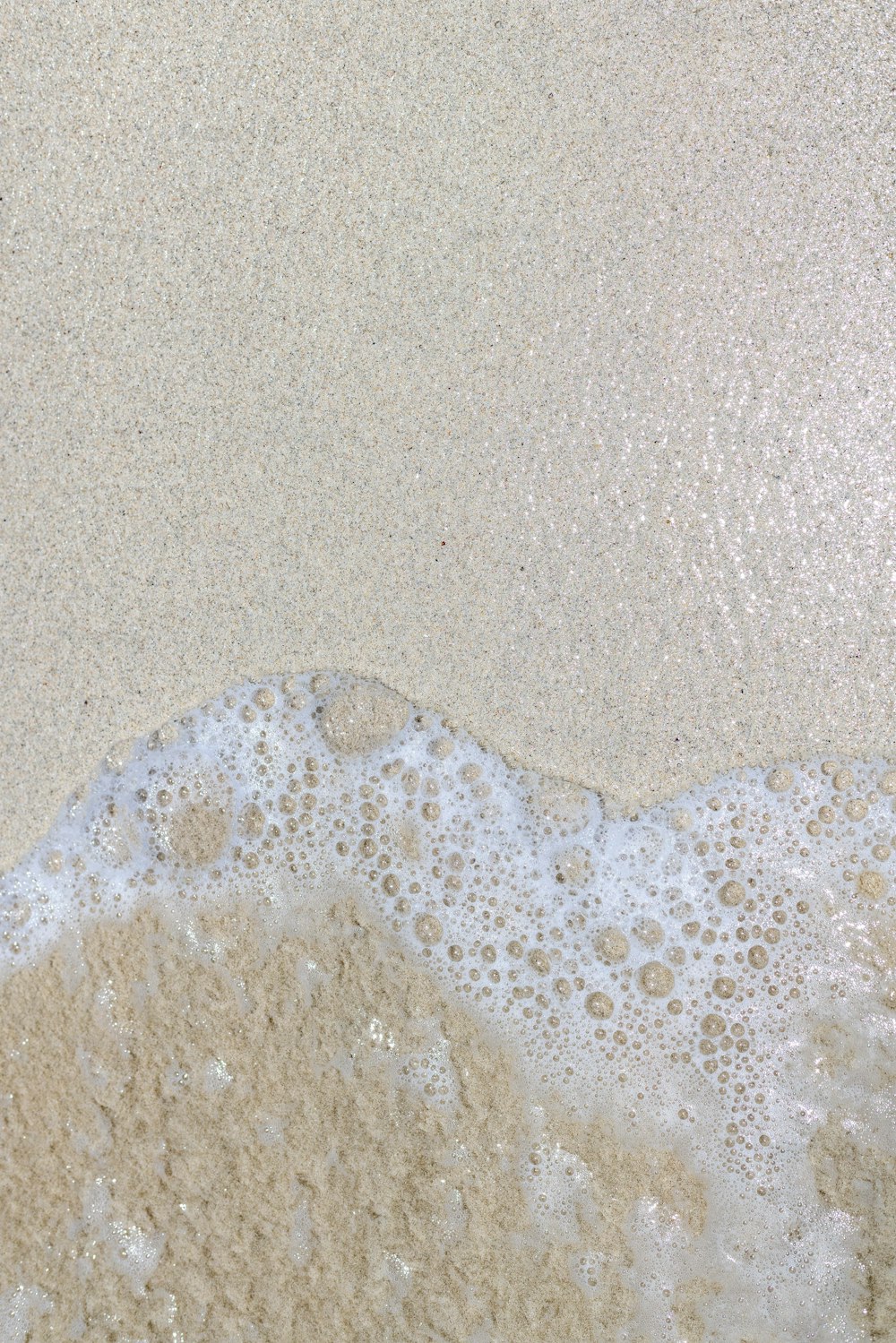 uma praia de areia com uma onda que vem para a costa