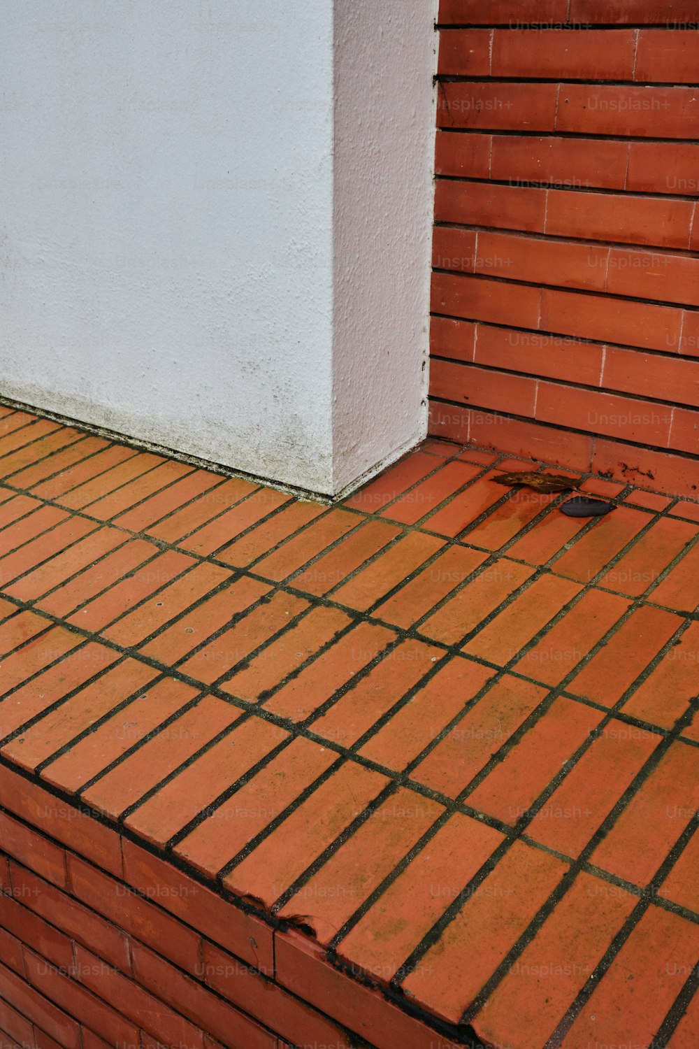 eine rote Backsteinmauer neben einem weißen Gebäude