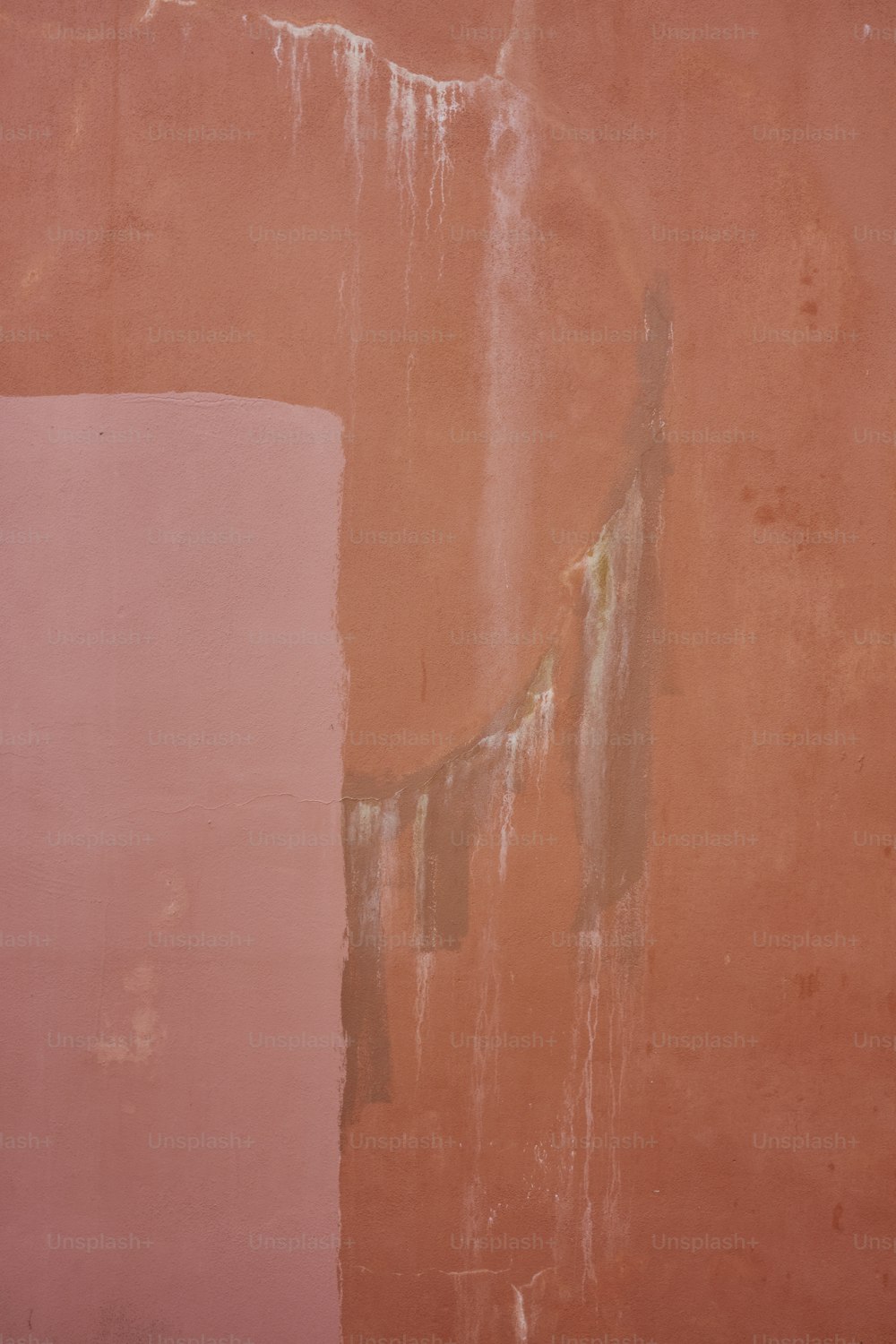 uma parede rosa com tinta descascando sobre ela
