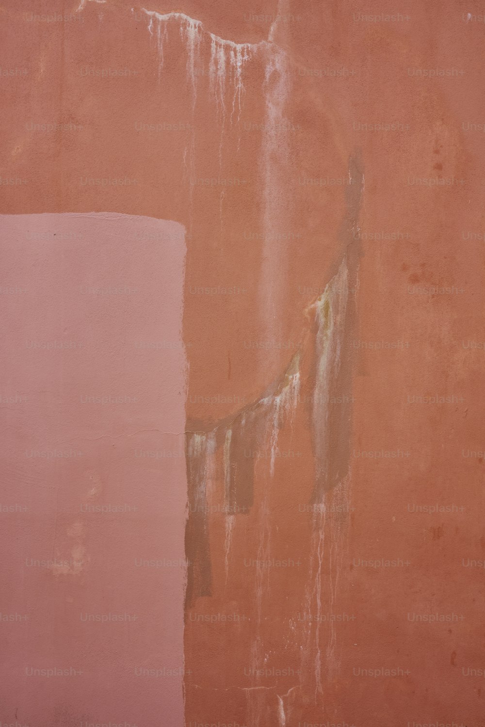 a pink wall with peeling paint on it