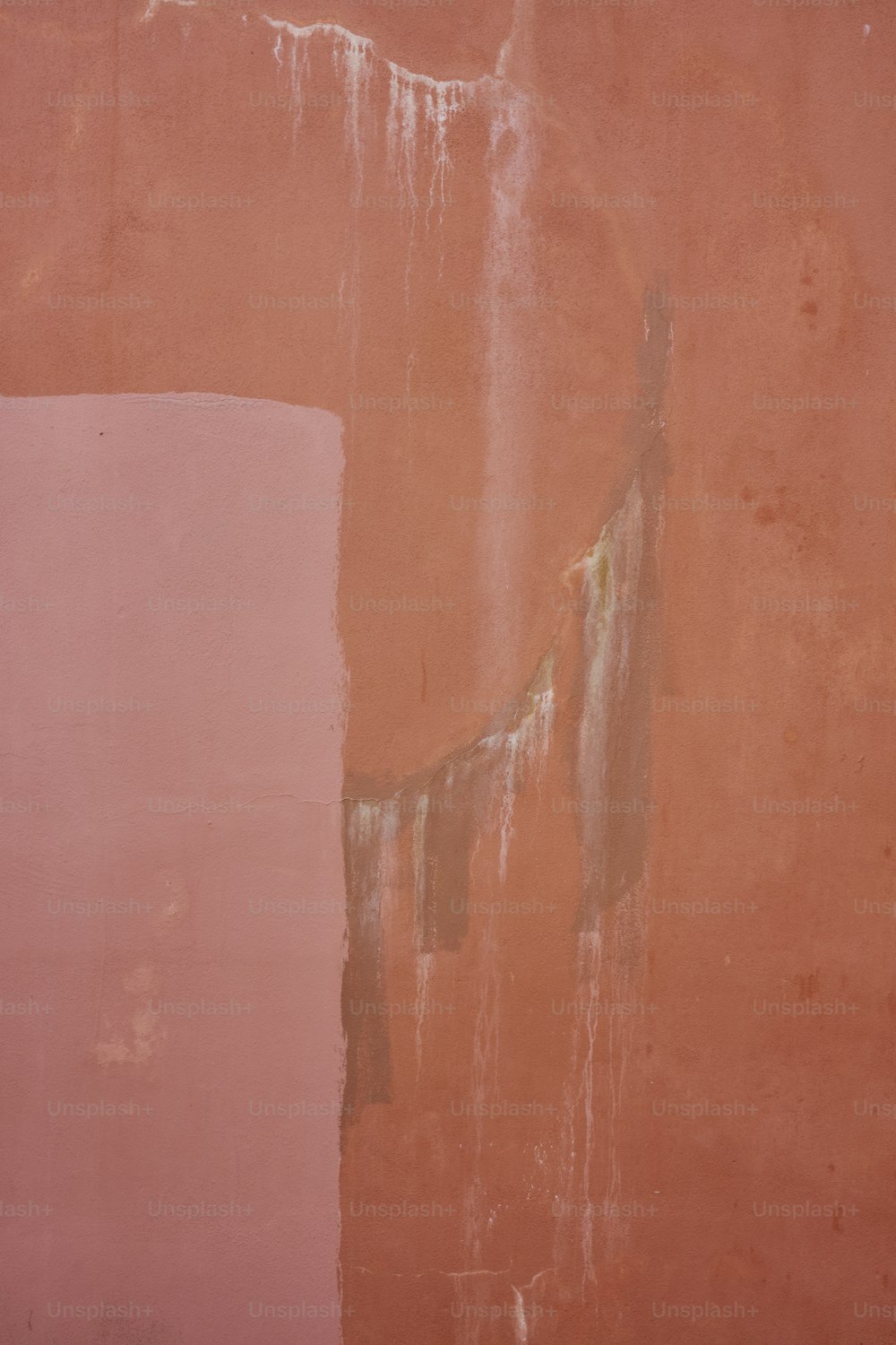 a pink wall with peeling paint on it