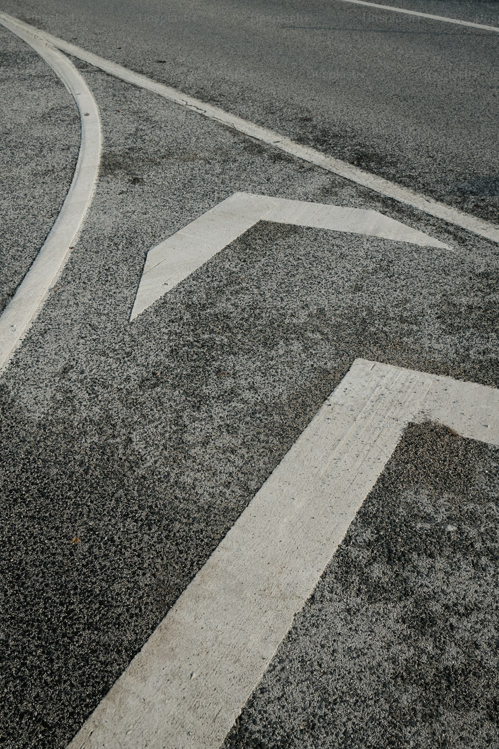 an arrow painted on the side of a road