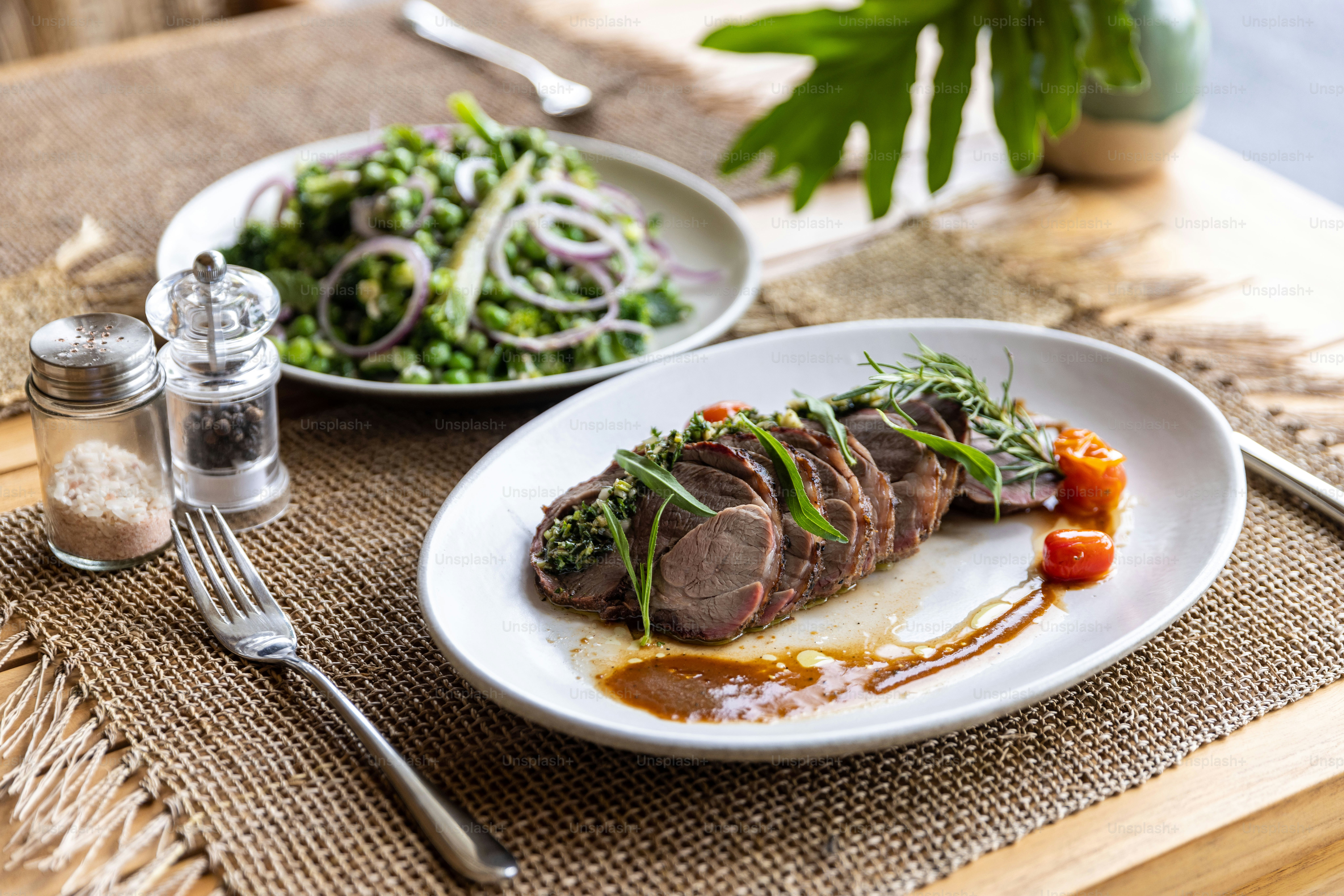 a white plate topped with meat next to a salad
