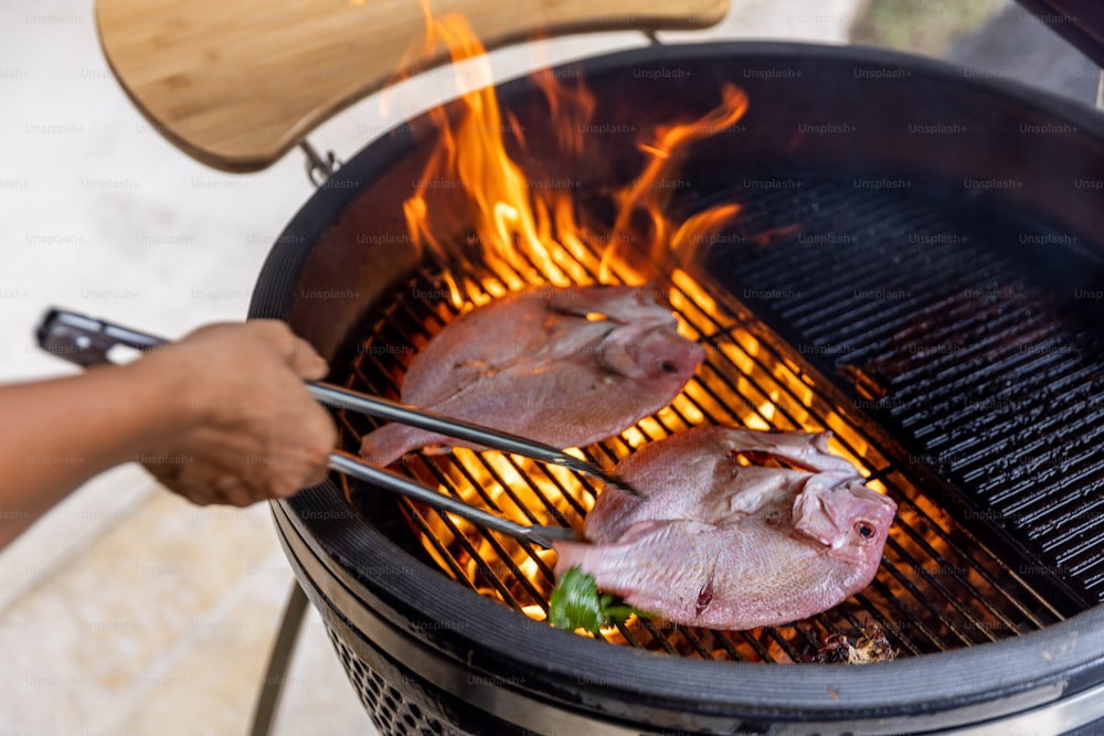 a person grilling meat on a grill with tongs