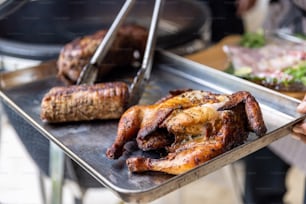 a person holding a tray with meat on it