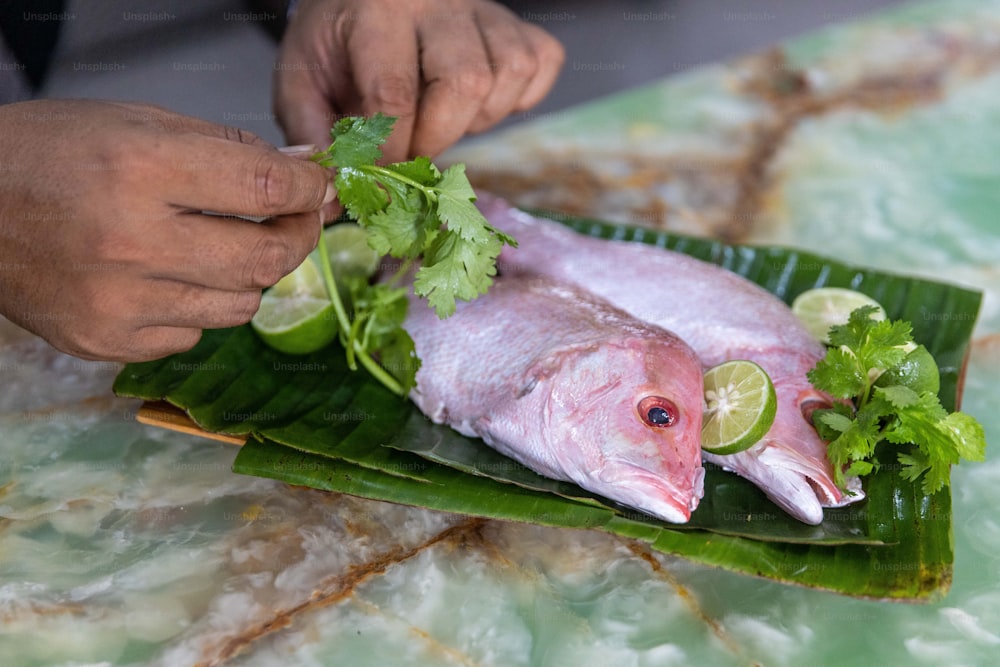 a person cutting up a fish on a banana leaf