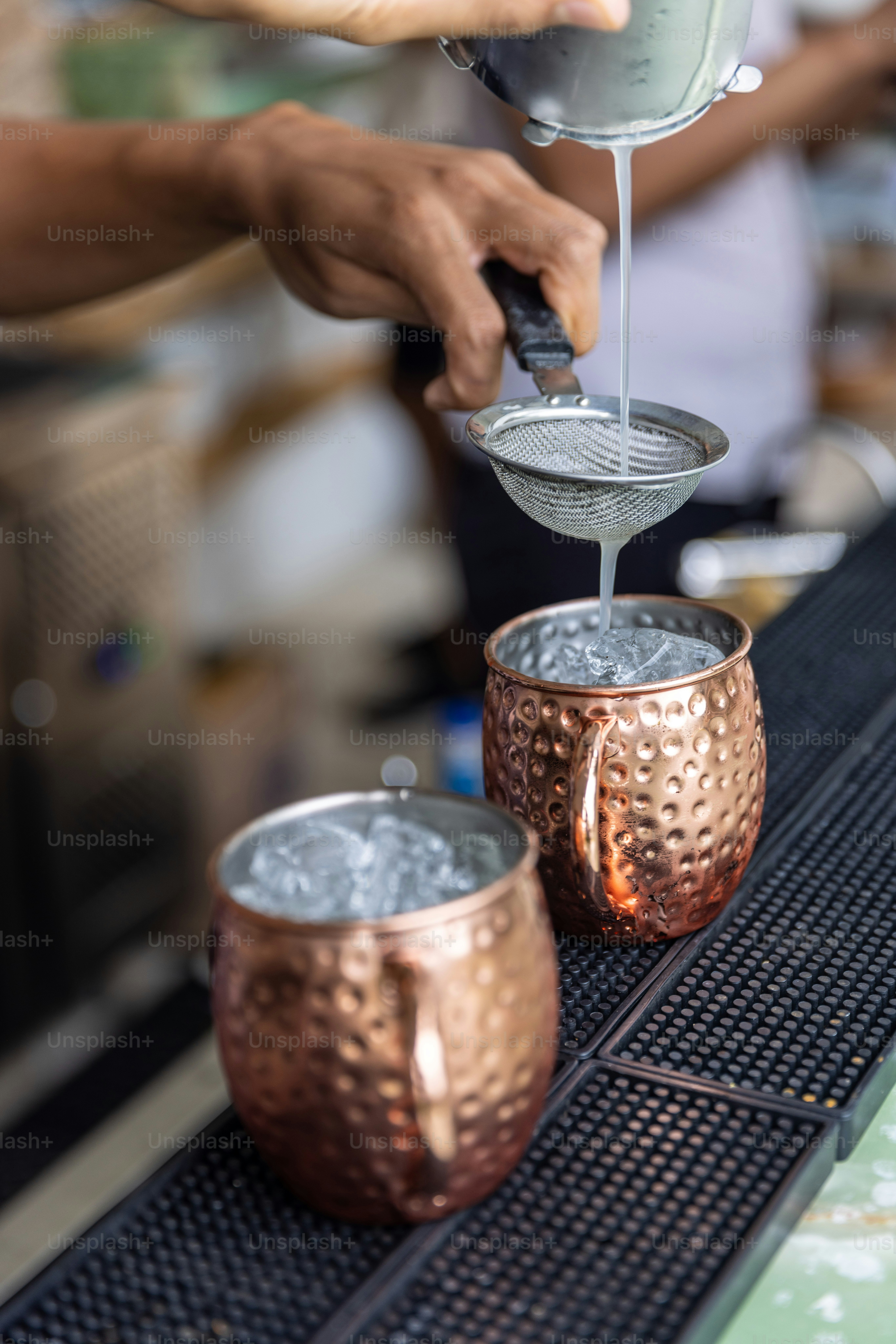 a person pouring a drink into two cups